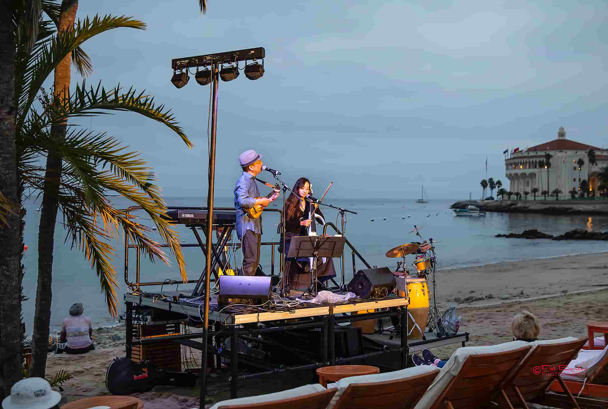  But 1st each JazzTrax Festival Weekend begins …  on Descanso Beach. An Unplugged Concert Under the Stars .. with the Blue Pacific Ocean rolling in .. right behind the tiny intimate on the Sand Performance Stage.This is Opening Night, Thursday, October 13th with Daniel Ho and his cello accompanist Danni Xue on stage to kick off our 35th October Festival .. Daniel has won 6 Grammy Awards and been Grammy Nominated 14 Times in the Hawaiian, Pop Instrumental and World Music Categories. But what JazzTrax Festival Goers know him for most .. he was the leader, composer, keyboardist of the very popular 1990’s band Kilauea who appeared here on the Island many times before disbanding end of the 90’s … however we’ve reunited them once …. and ….. stay tuned We always encourage all festival goers who arrive an Evening Early for our Beach concert, to spend ALL of Thursday Evening at Descanso Beach Club.  Beach Bar to order food and drink opens at 5 p.m. with 2 hours of daylight left over the ocean.  Do Dinner there as many of you have 2 romantically doubled up Chaise Lounges and other a Private Cabana. Take the Entire Evening There for Beach, Food, Drink, and Shows.  